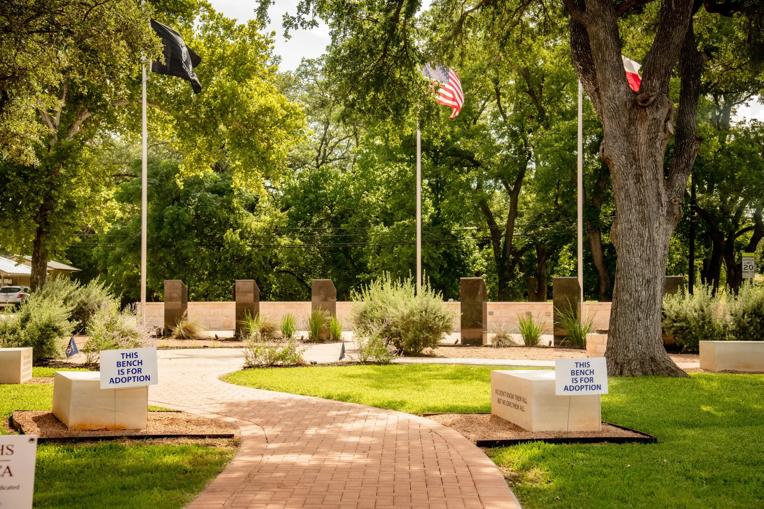 The Blanco County Veterans Memorial, with its flags flying beside a large oak tree